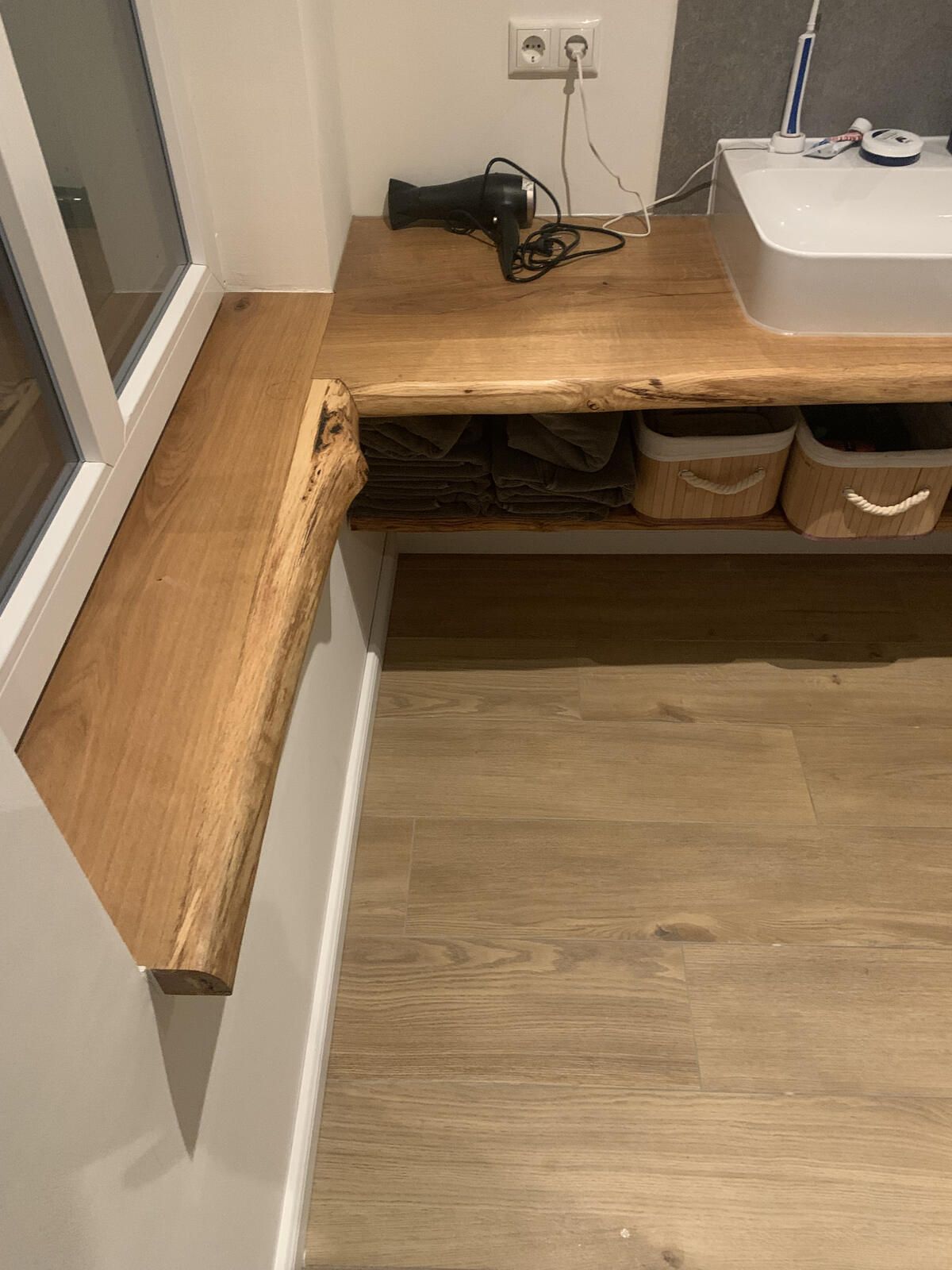 Ein Badezimmer mit Holzablage und Waschbecken.