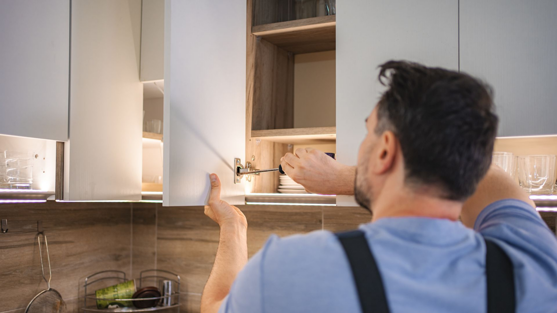 Artisan qui resserre une vis sur un placard de cuisine