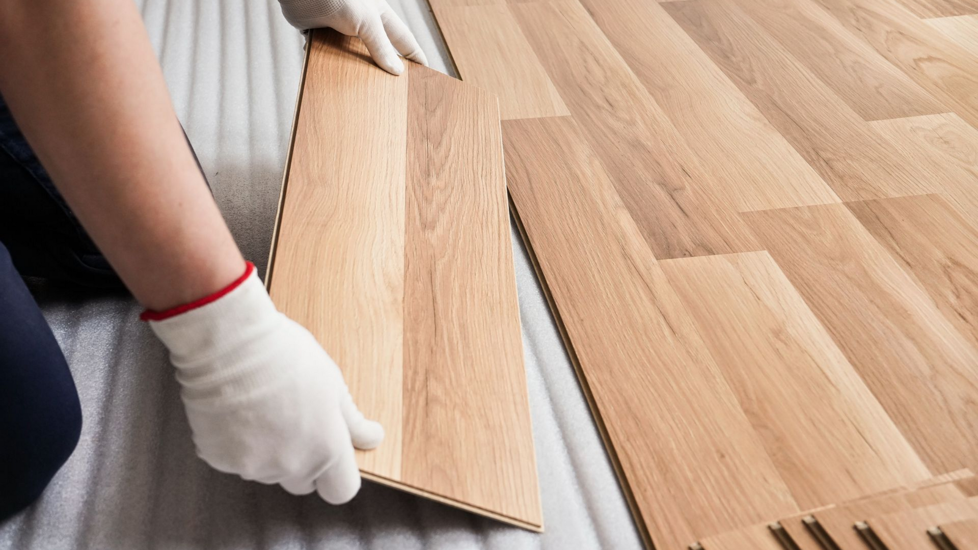 Mains préparant des lames de parquet pour la pose