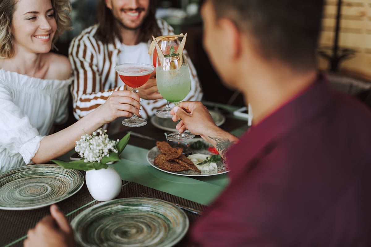 Un grupo de personas está sentada en una mesa con platos de comida y bebidas.