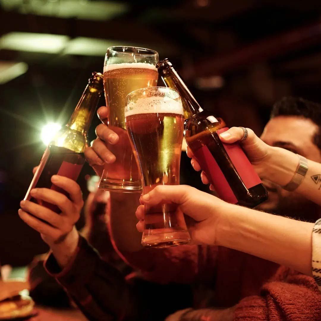 Un grupo de personas brindando con botellas de cerveza y vasos.