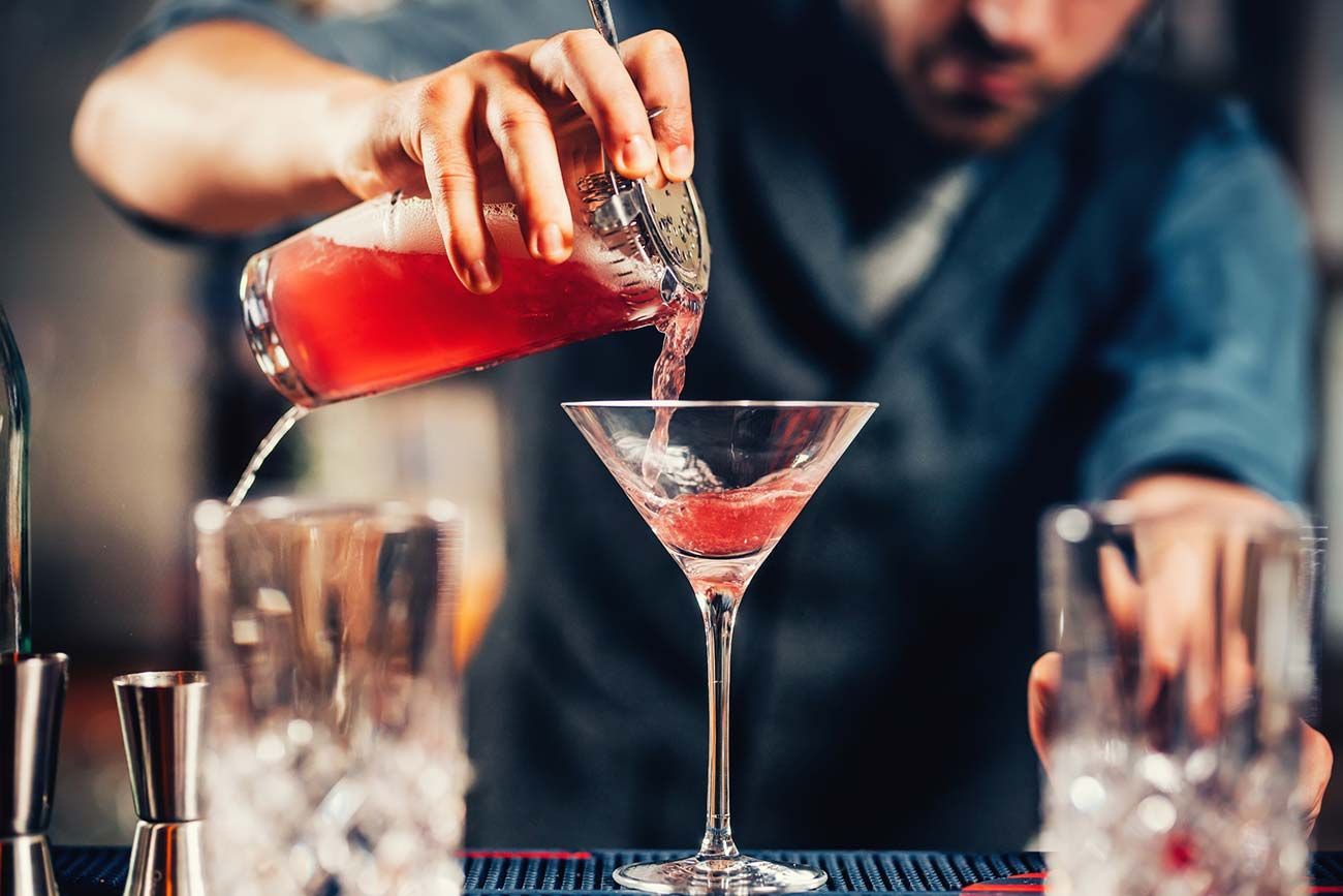 Un camarero está sirviendo una bebida en una copa de martini.