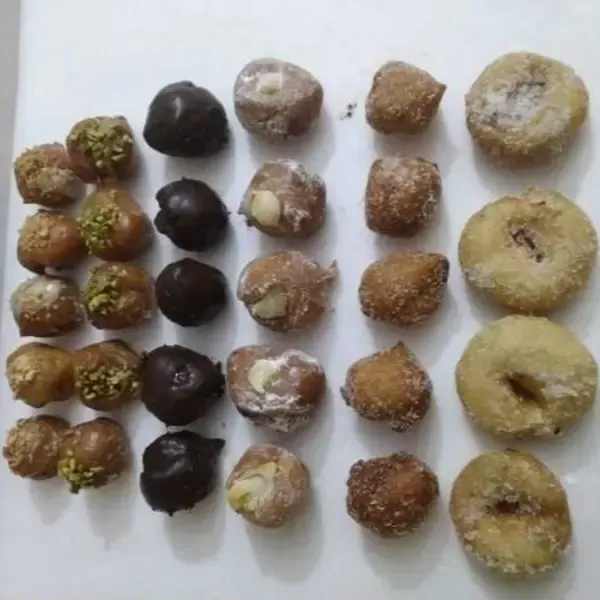 Diversos pasteles pequeños y redondos, incluyendo bocaditos cubiertos de pistacho, de chocolate y otros sencillos.