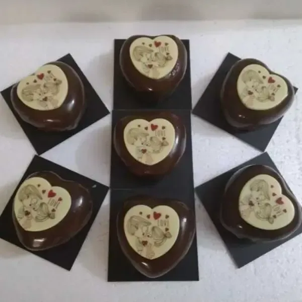 Seis bombones con forma de corazón, cada uno decorado con una ilustración romántica sobre un fondo blanco.