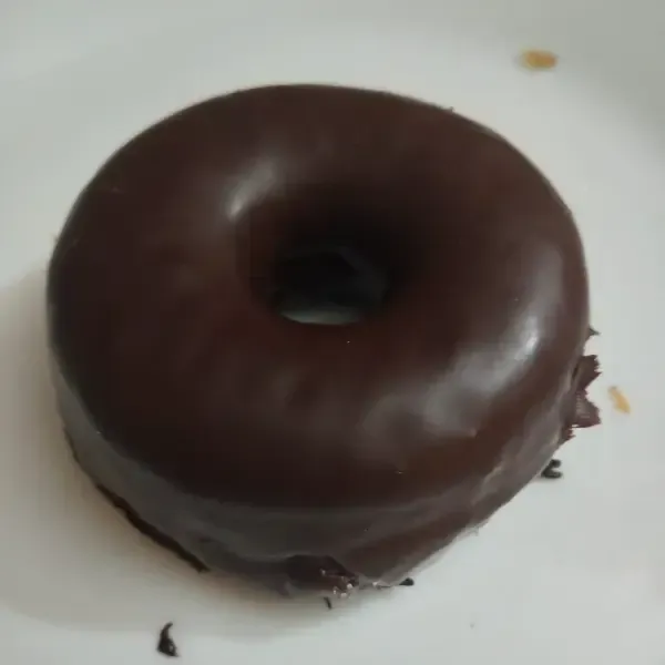 Un único donut glaseado de chocolate, colocado en el centro de un plato blanco.