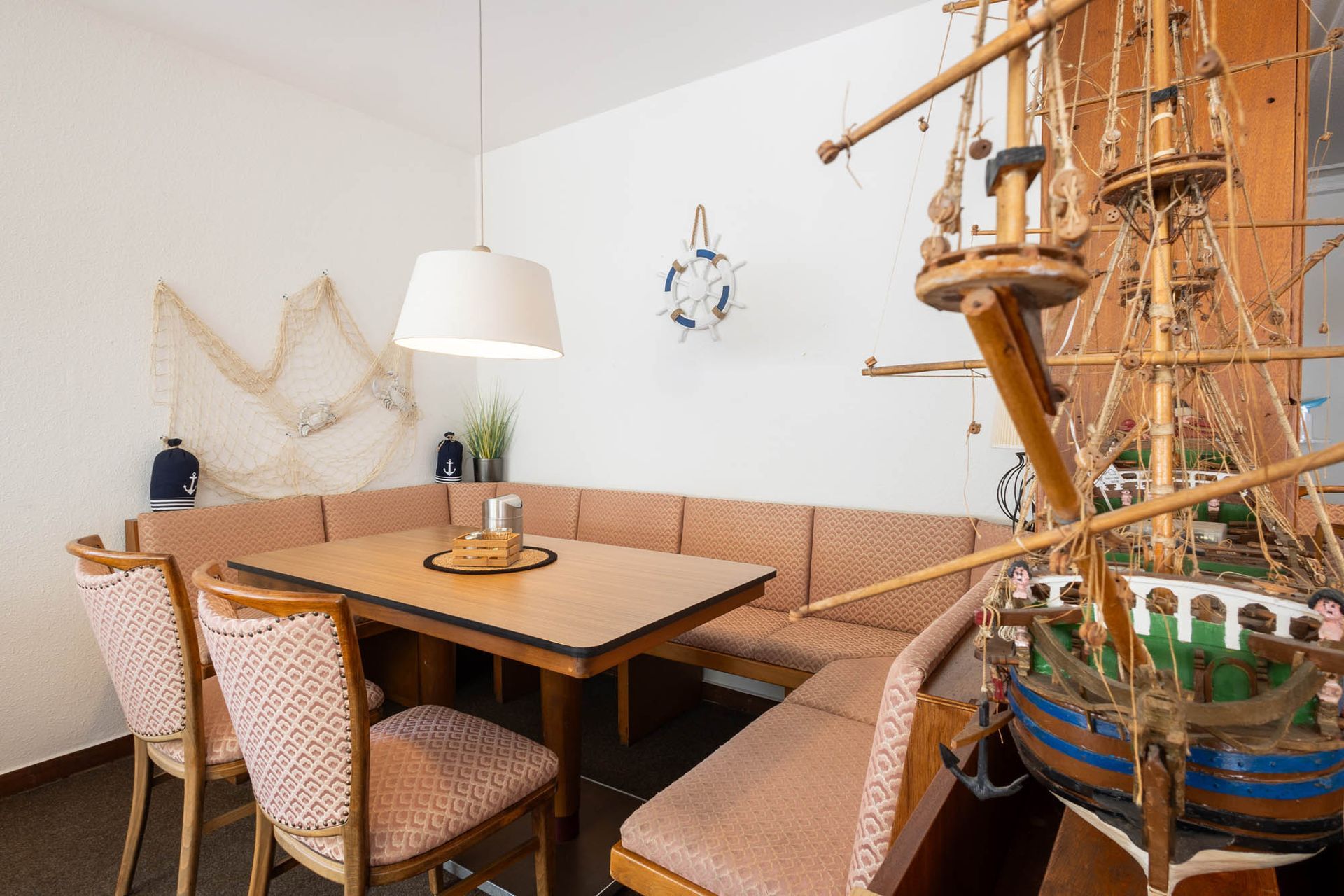 Ein Esszimmer mit Tisch und Stühlen und einem Schiffsmodell.