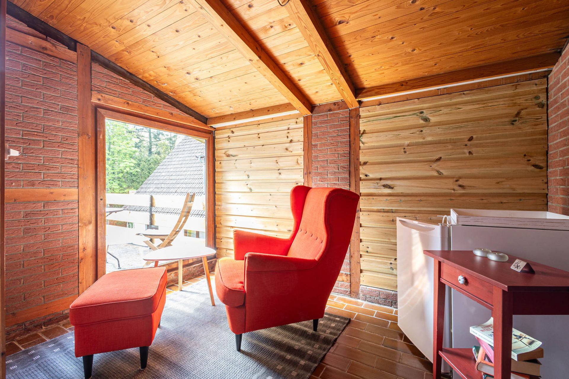 Ein Wohnzimmer mit einem roten Sessel und Ottomane