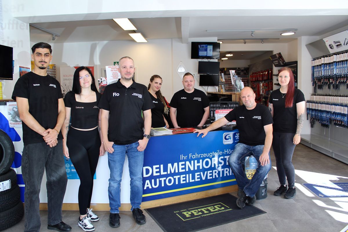 Seven staff members in matching black shirts stand behind a sales counter at Delmenhorst Autoteilevertrieb.