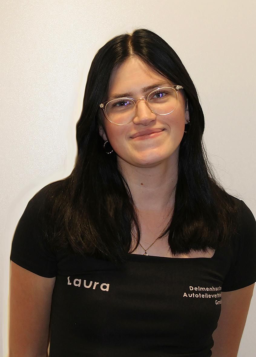 Eine Person mit dunklen Haaren und Brille trägt ein schwarzes T-Shirt mit dem aufgedruckten Namen „Laura“ auf weißem Hintergrund.