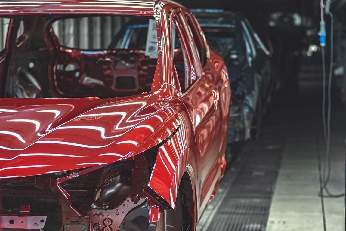 Un coche rojo está parado en una cinta transportadora en una fábrica.