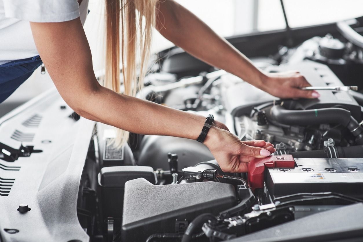 Una mujer está trabajando en el motor de un coche.