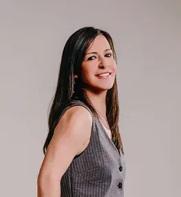 Una mujer lleva un chaleco gris y sonríe.