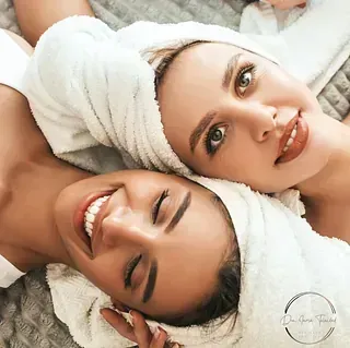 Dos mujeres están acostadas una al lado de la otra con toallas envueltas alrededor de sus cabezas.