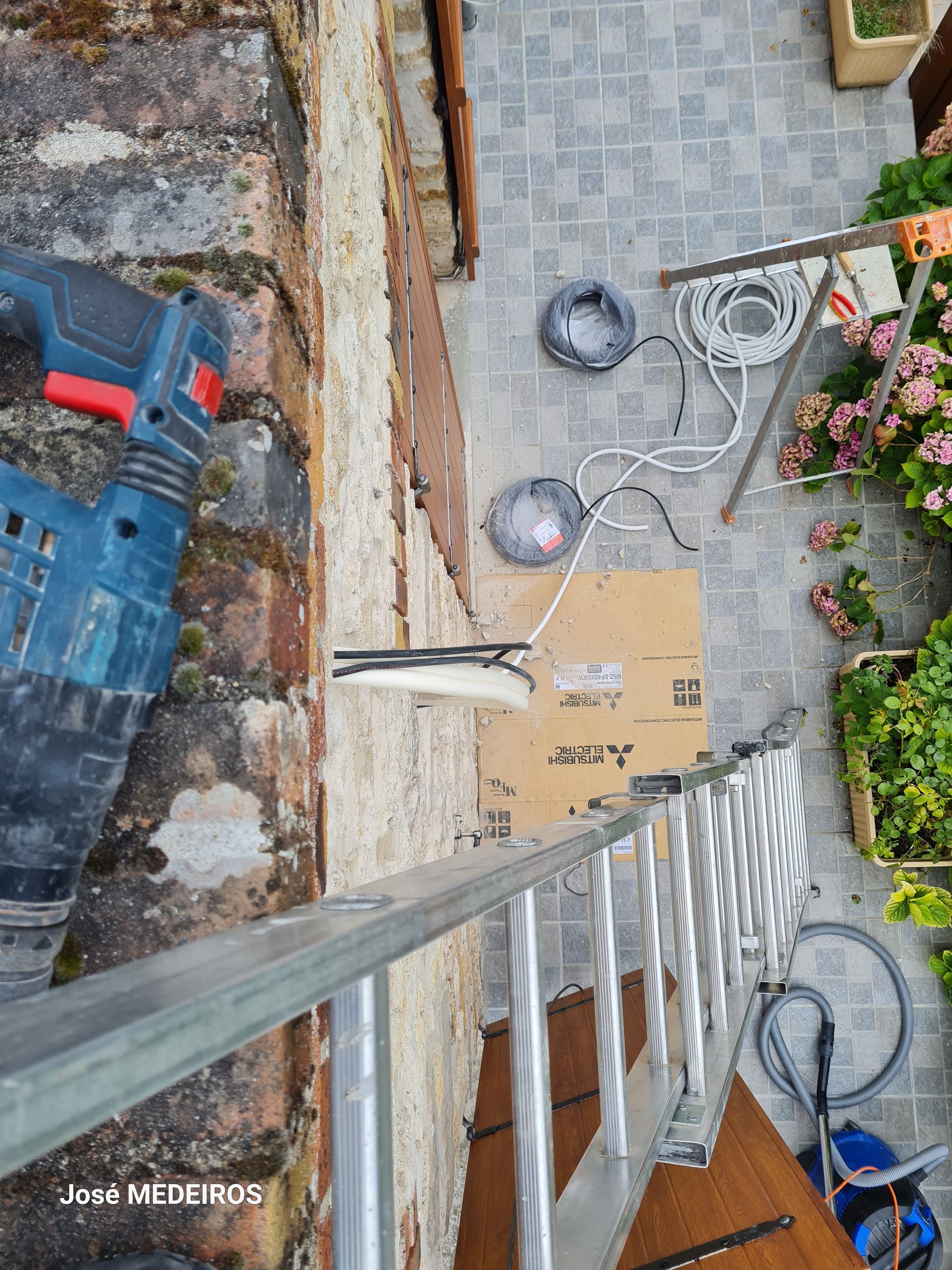 Echelle et sol extérieur d'une maison vue depuis le toit lors du raccordement électrique d'une unité extérieur de pompe à chaleur