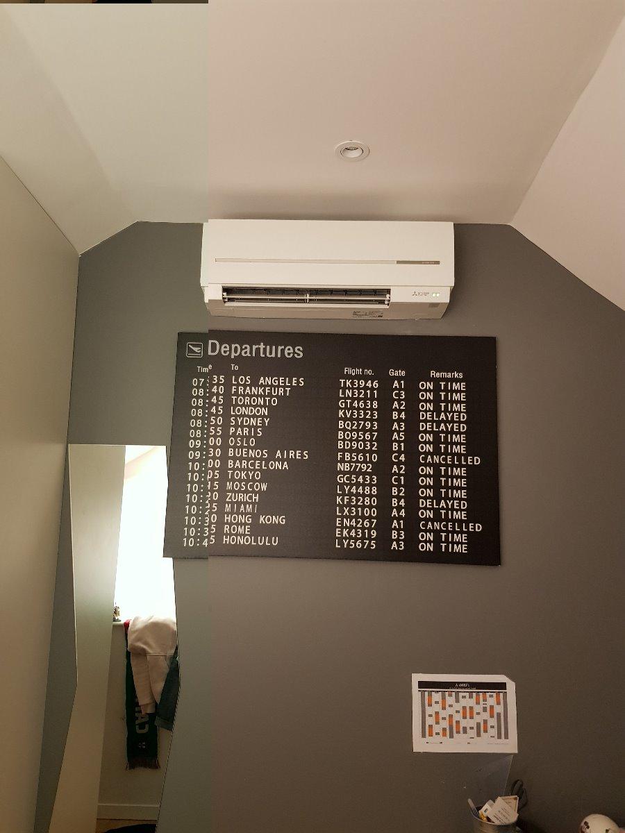 Climatisation murale posée au dessus d'une décoration inspirée étrangement d'un tableau d'aéroport