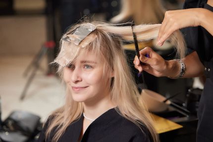 Una clienta rubia se está haciendo un corte de pelo con mechas en un salón de belleza.