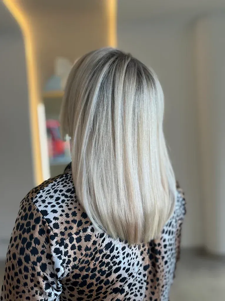 Mujer con cabello lacio y rubio, vistiendo un top estampado, en un espacio bien iluminado.