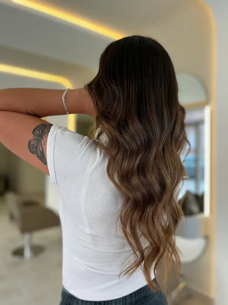 Mujer con cabello lacio y rubio, vistiendo un top estampado, en un espacio bien iluminado.