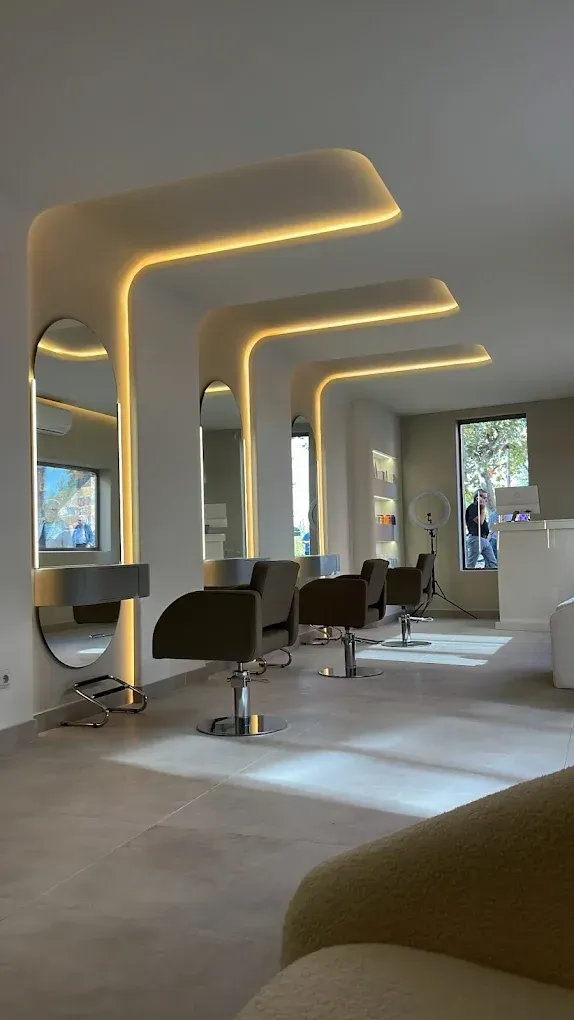 Interior de peluquería con espejos, sillas e iluminación suave.