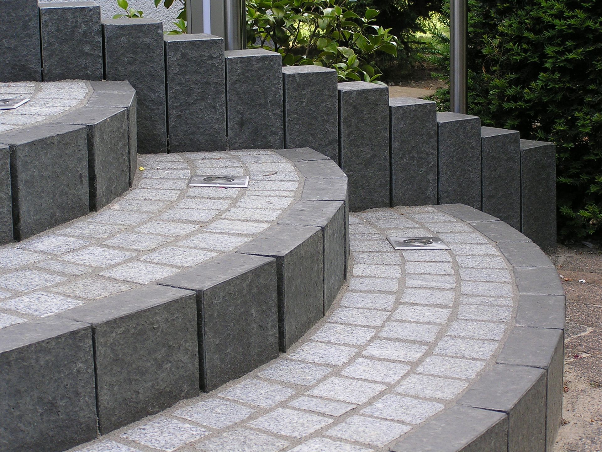 Geschwungene Steinstufen, graue Granitblöcke, strukturierte Oberfläche, Außenbereich.