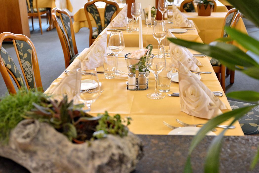 Schön gedeckter Tisch mit gelber Decke und vielen Gläsern im Restaurant