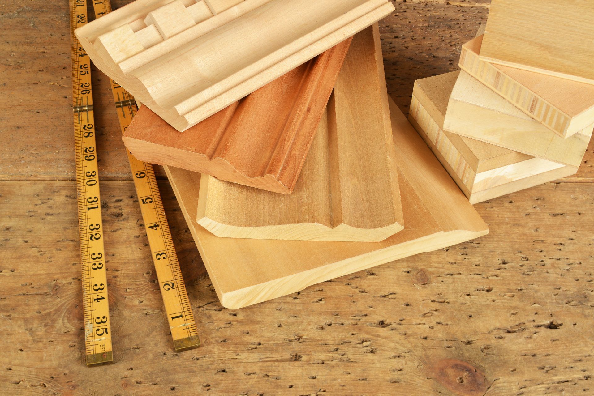 Una pila de molduras de madera y una regla sobre una mesa de madera.