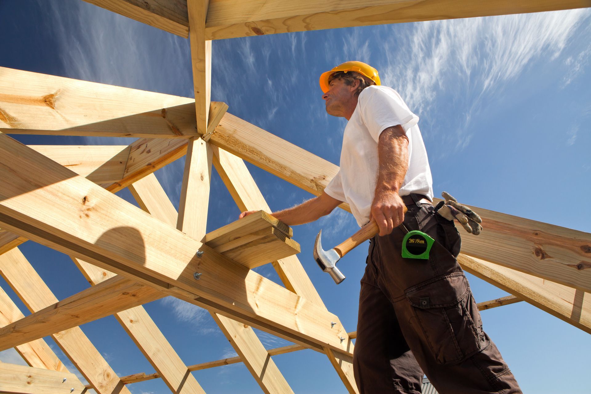 Un hombre está trabajando en una estructura de madera con un martillo.