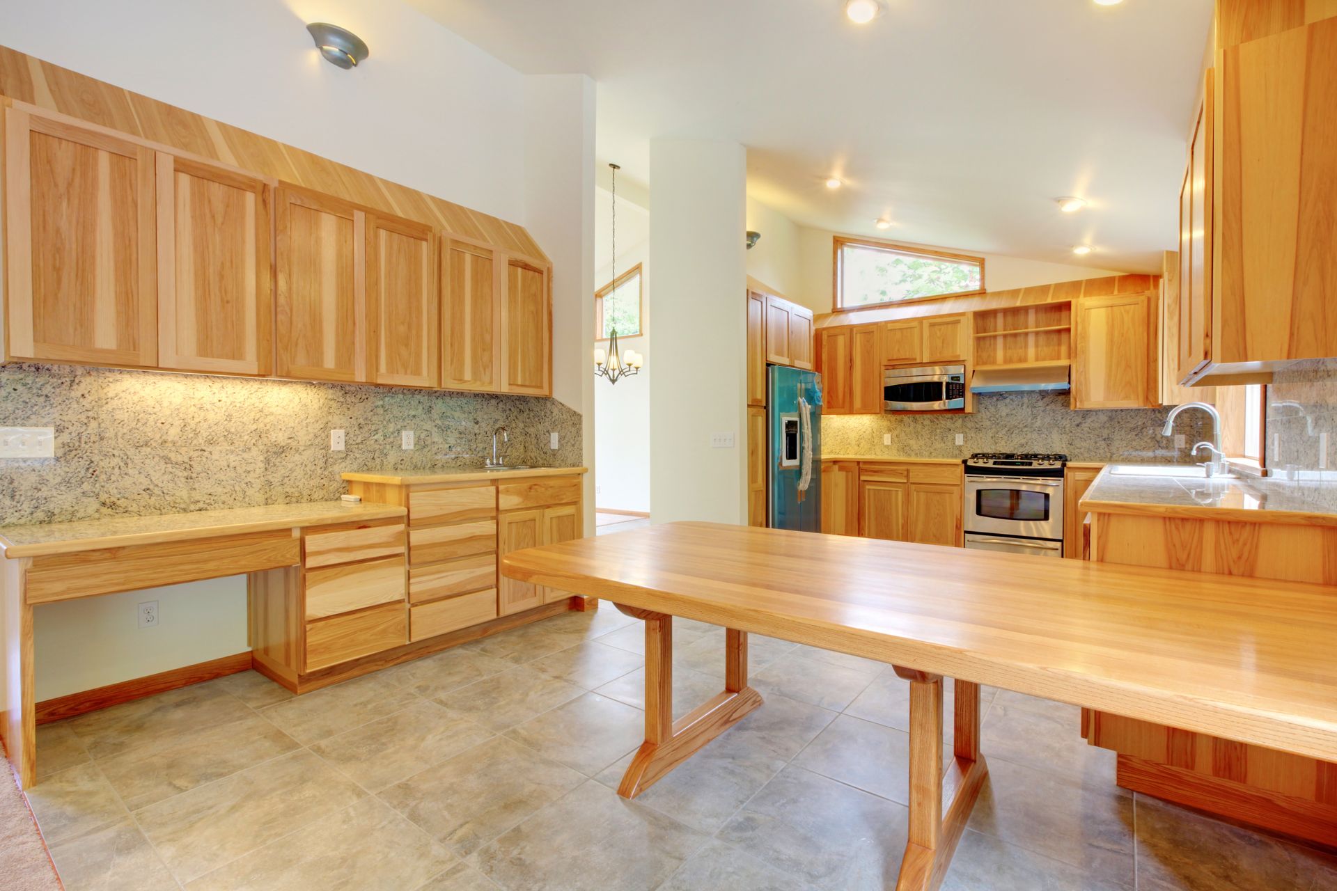 Una cocina vacía con gabinetes de madera y una mesa larga de madera.