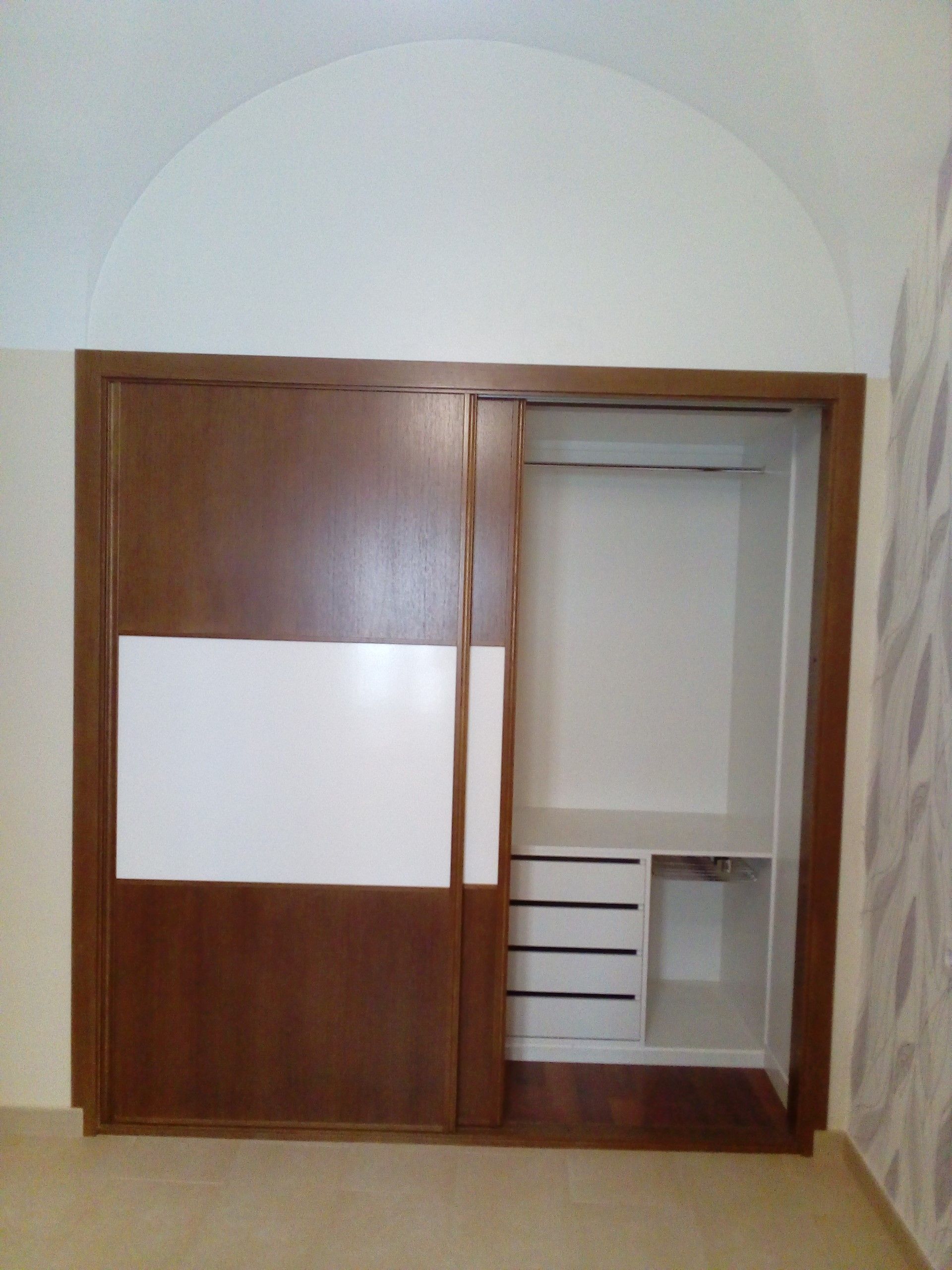 Un armario con puertas correderas y cajones en una habitación.