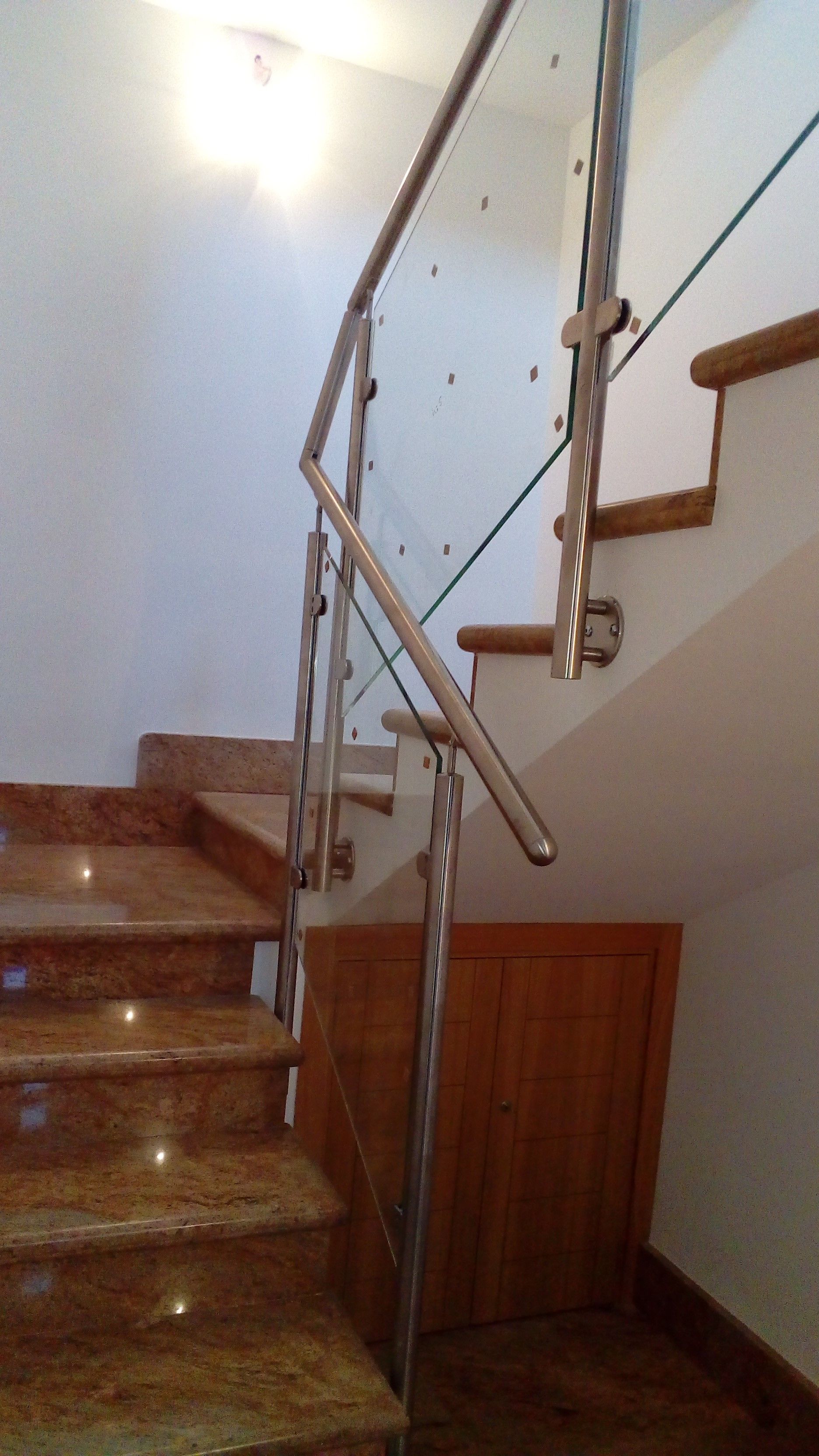 Una escalera con barandilla de acero inoxidable y barandilla de vidrio.