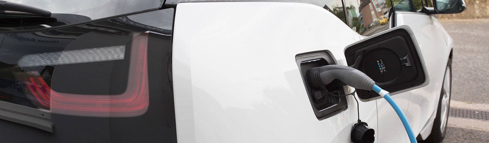 Ein weißes Elektroauto wird an einer Ladestation aufgeladen.