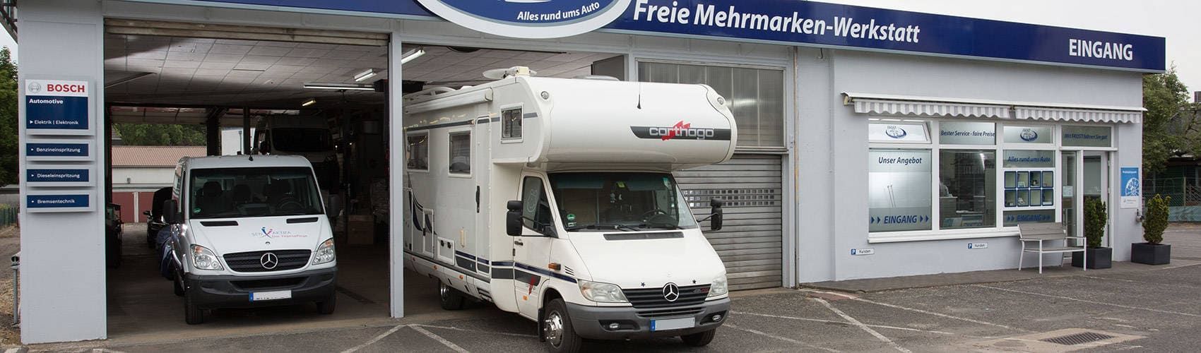 Ein weißer Lieferwagen und ein weißes Wohnmobil stehen vor einem Gebäude.
