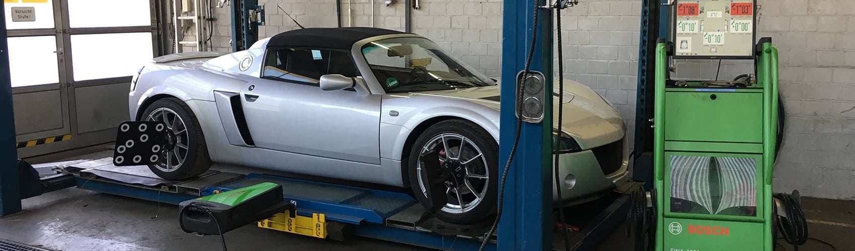 Ein silberner Sportwagen steht auf einer Hebebühne in einer Garage