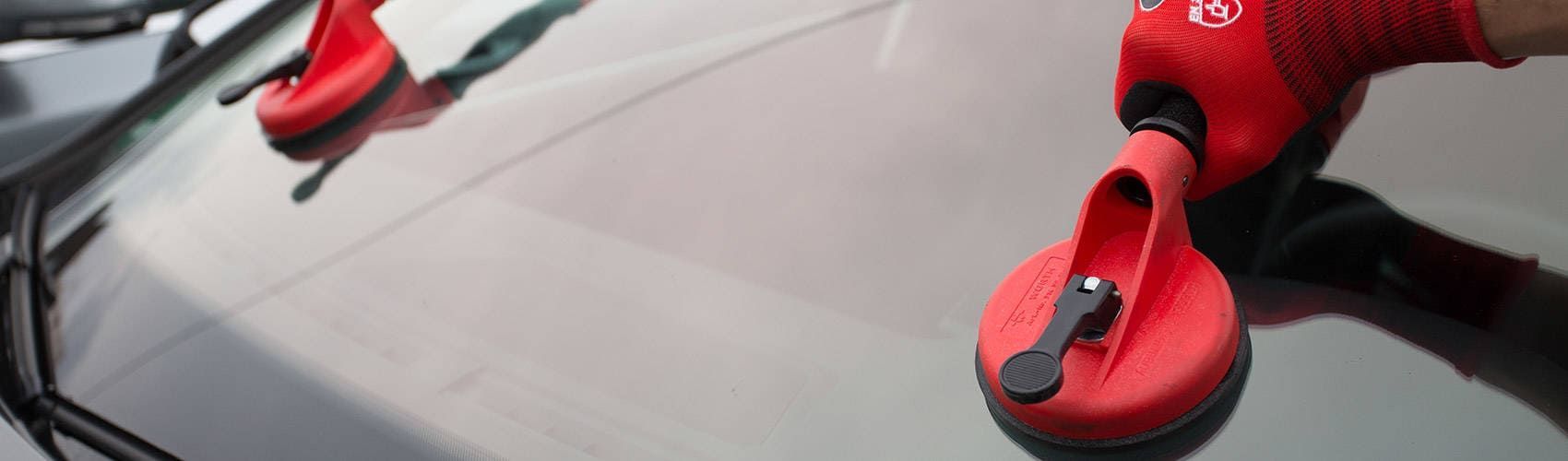 Eine Person montiert eine Windschutzscheibe an einem Auto.