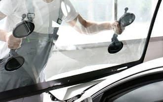 Ein Mann montiert eine Windschutzscheibe an einem Auto.