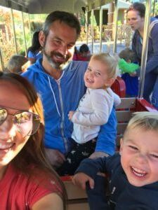 Four people smiling on a carousel ride, including two children and two adults.