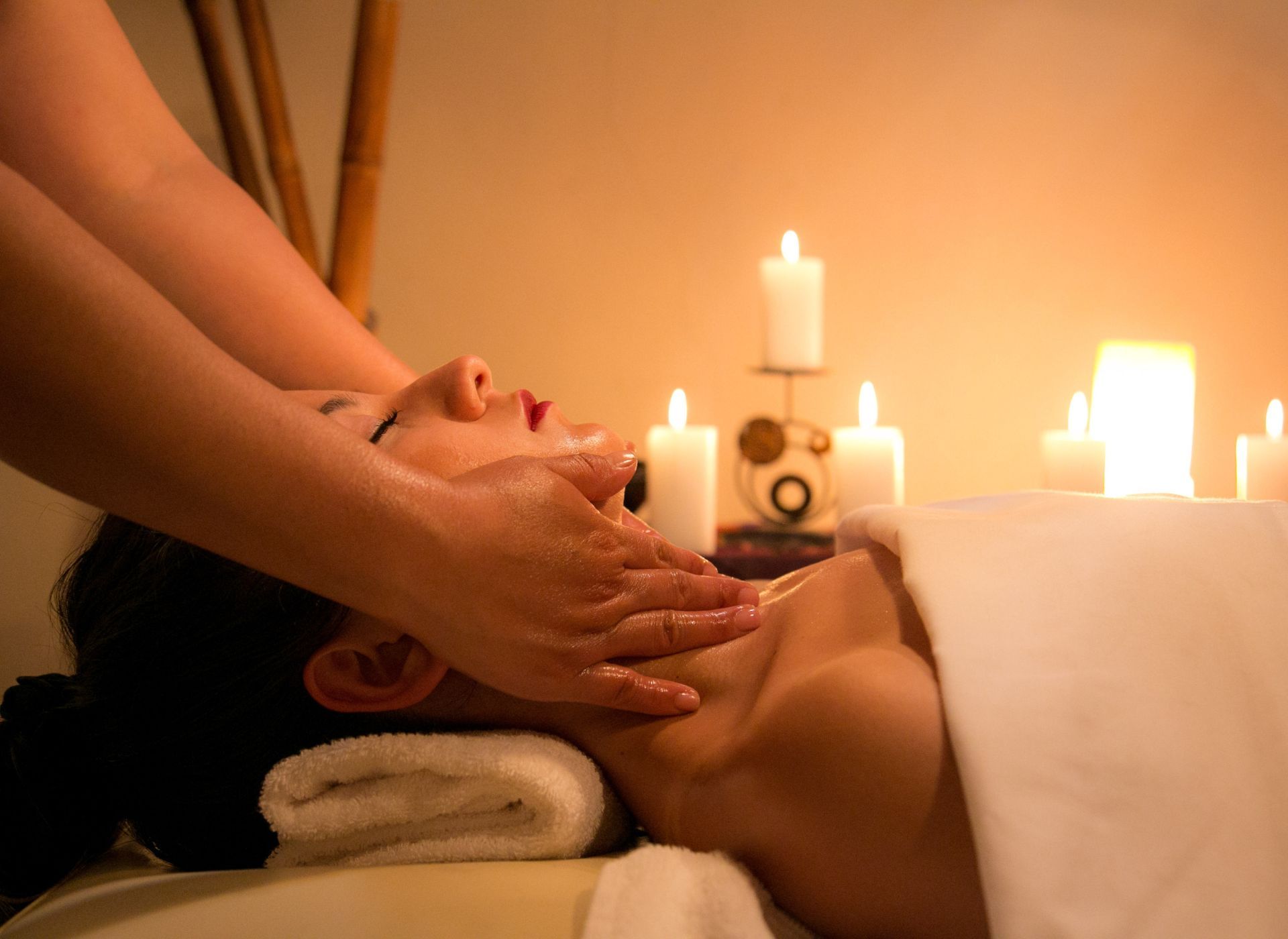 Spa massage with candles, showing a person receiving a facial massage in a dimly lit room