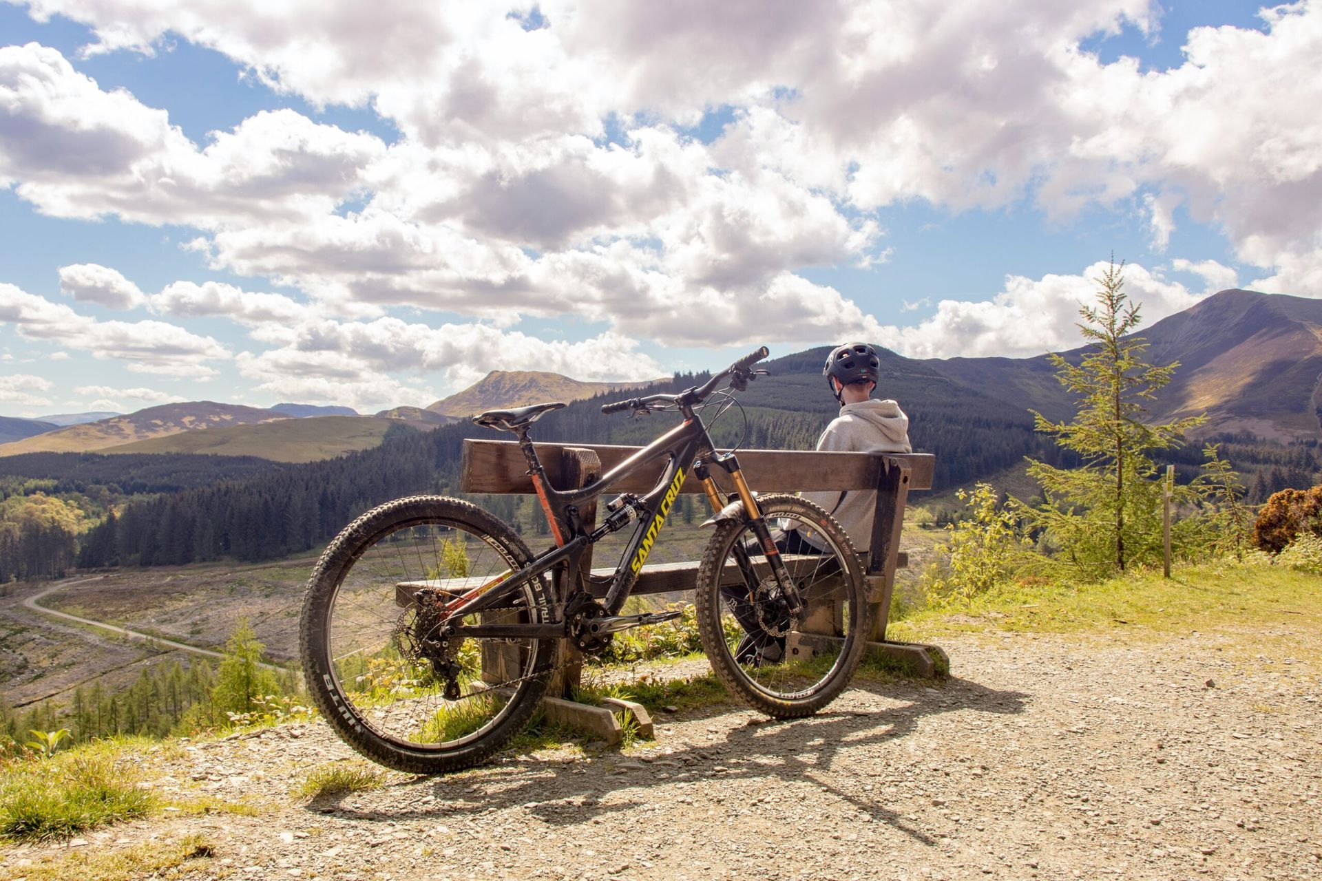 Person on a fat-tire bike with a child trailer on a mountain overlook under a cloudy sky