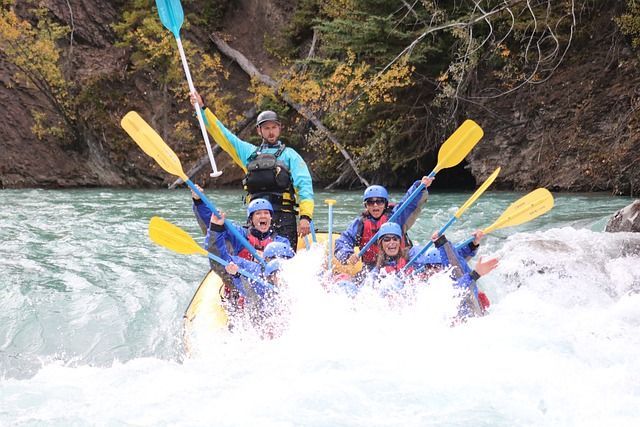 Whitewater rafters paddling through rapids, splashing water in a canyon river.