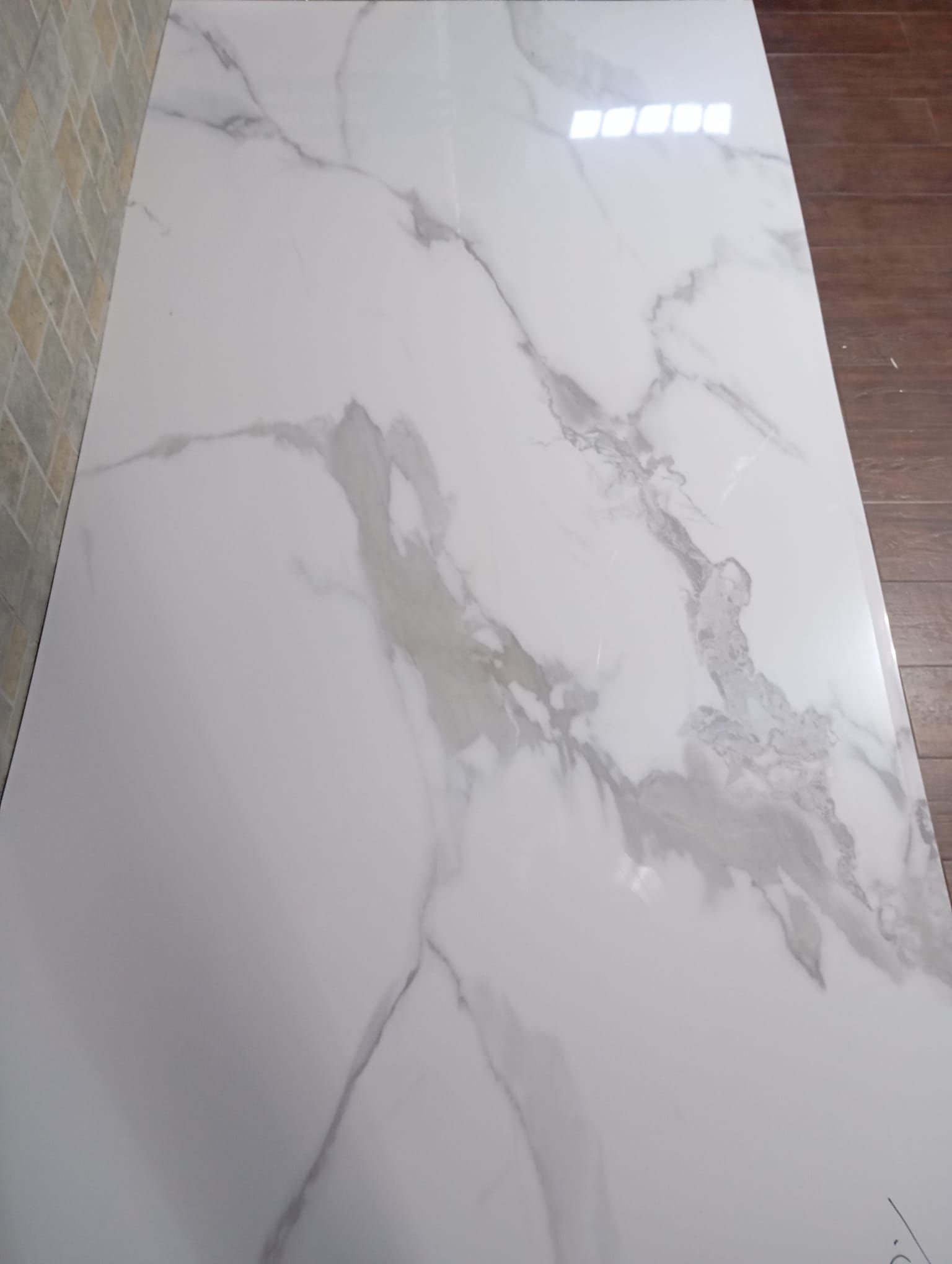 Una gran baldosa de mármol blanco reposa sobre un piso de madera.