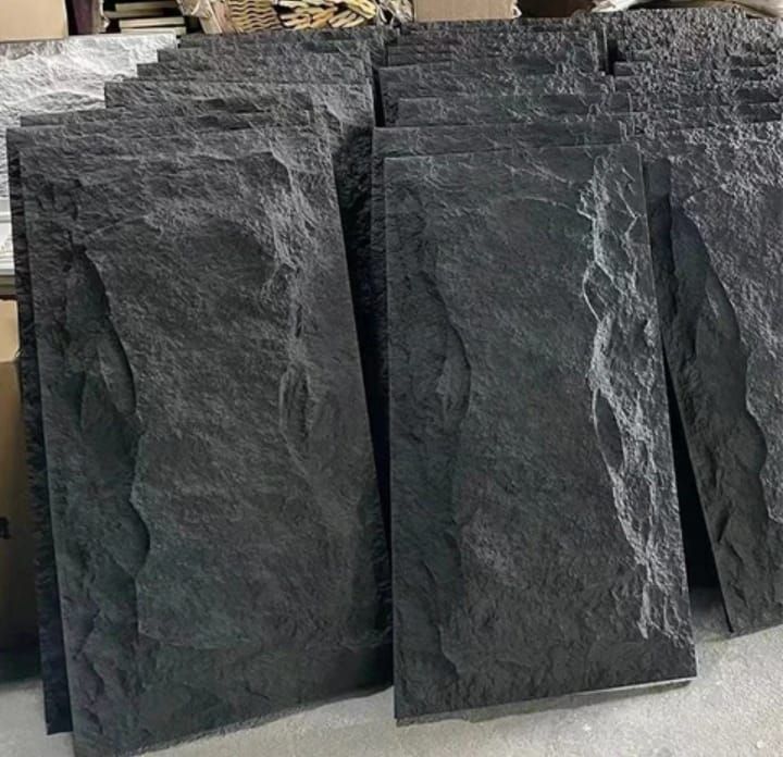 Un montón de baldosas negras están apiladas una encima de otra en el suelo.