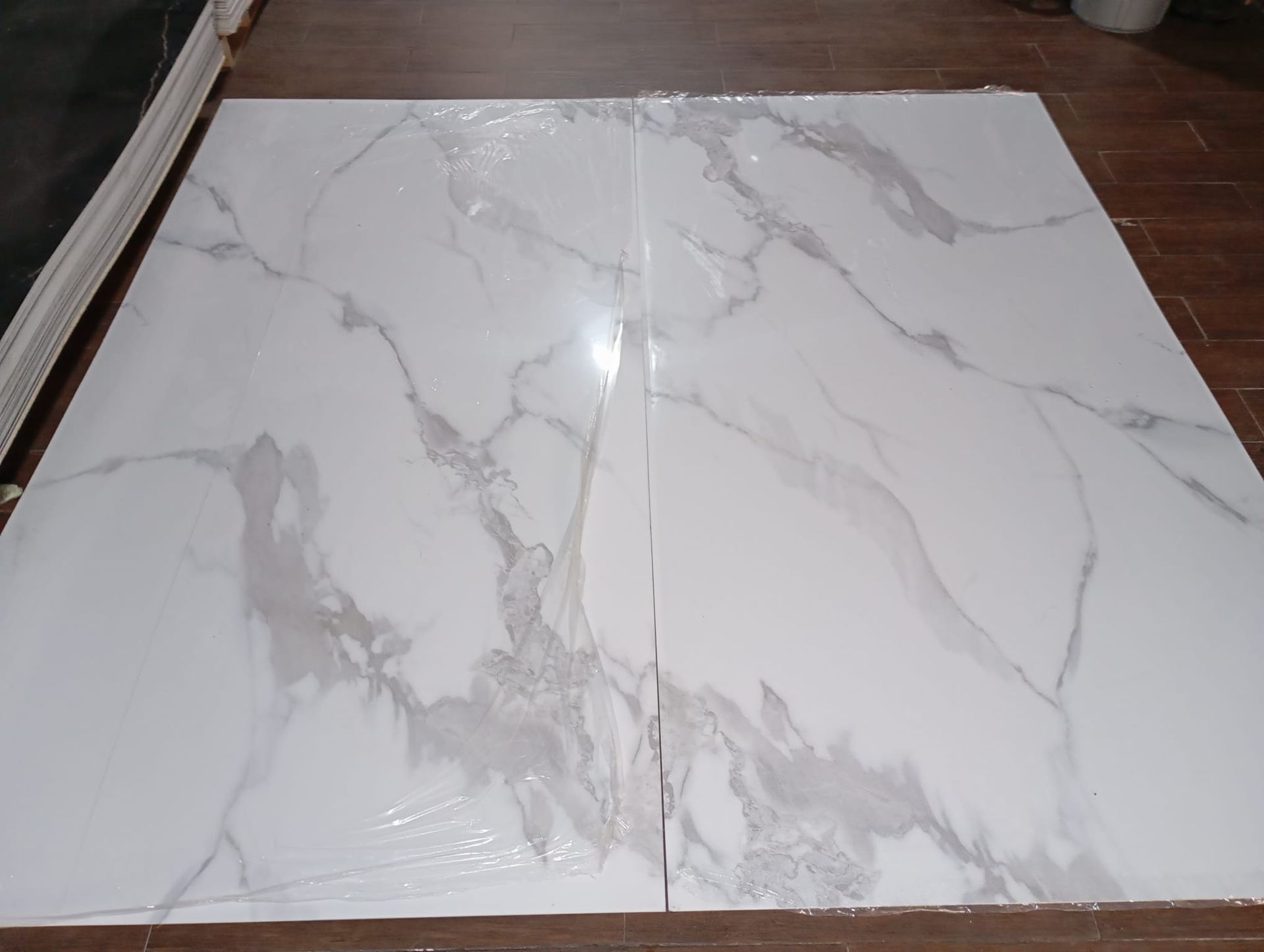 Dos baldosas de mármol blanco se encuentran sobre un piso de madera.