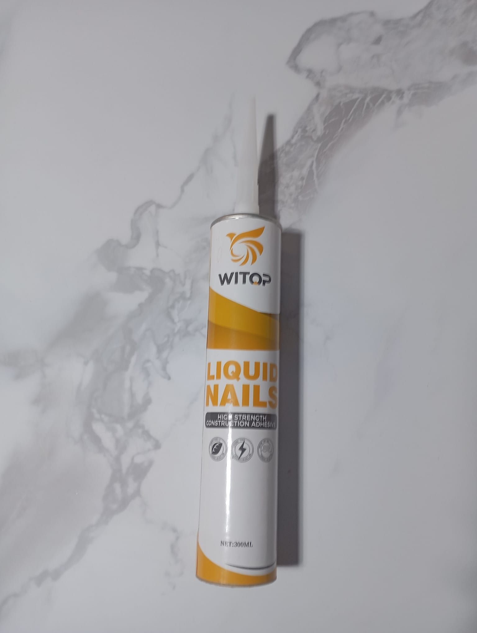 Una lata de clavos líquidos está sobre una superficie blanca.