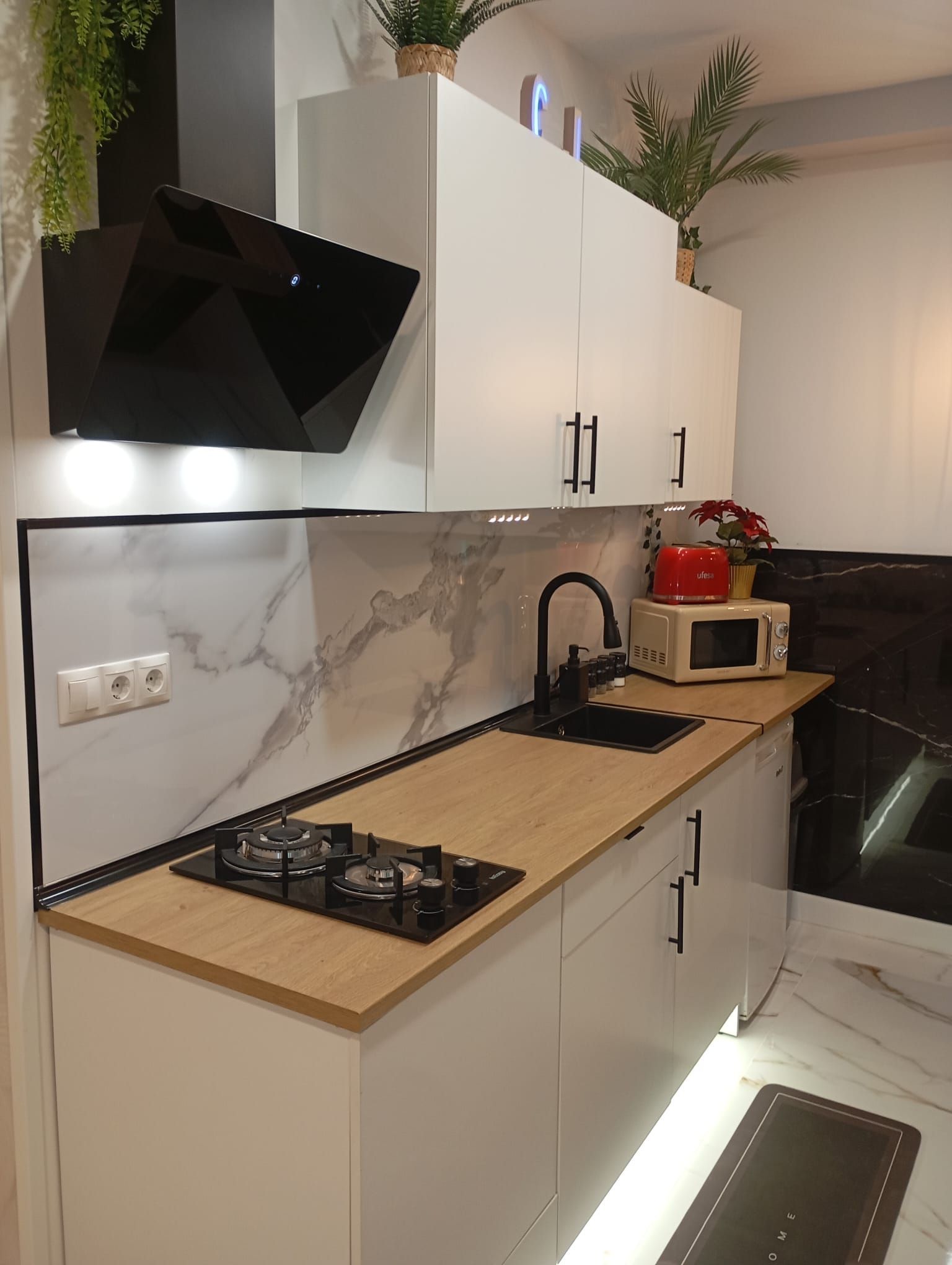 Una cocina con gabinetes blancos, un horno de estufa, un fregadero y un microondas.