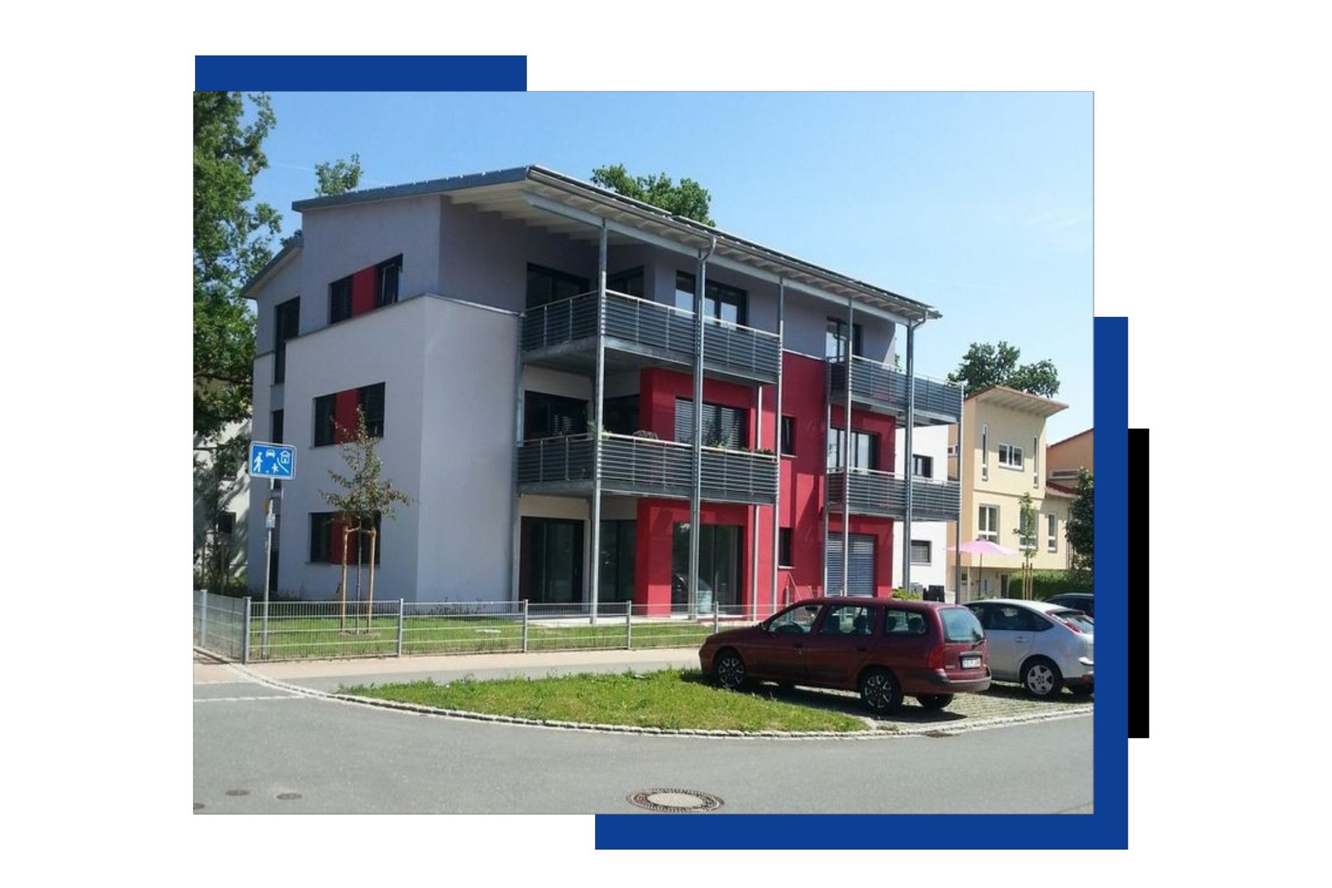 Vor einem Gebäude parkt ein rotes Auto.