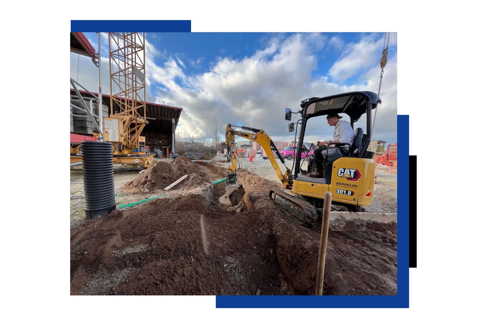 Ein Mann fährt einen kleinen Bagger auf einer Baustelle.