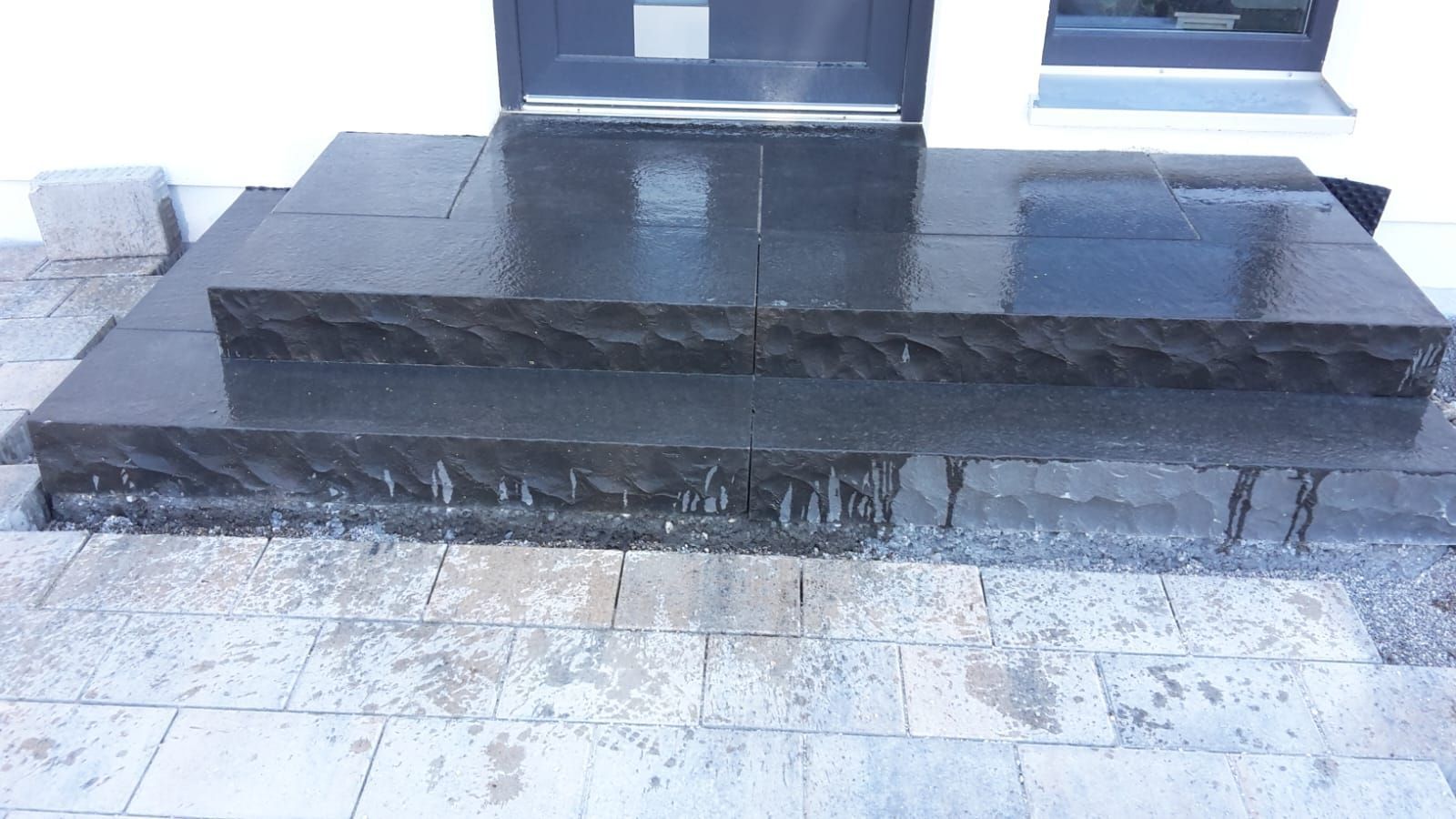 Dunkle Steinstufen vor moderner Hausfassade