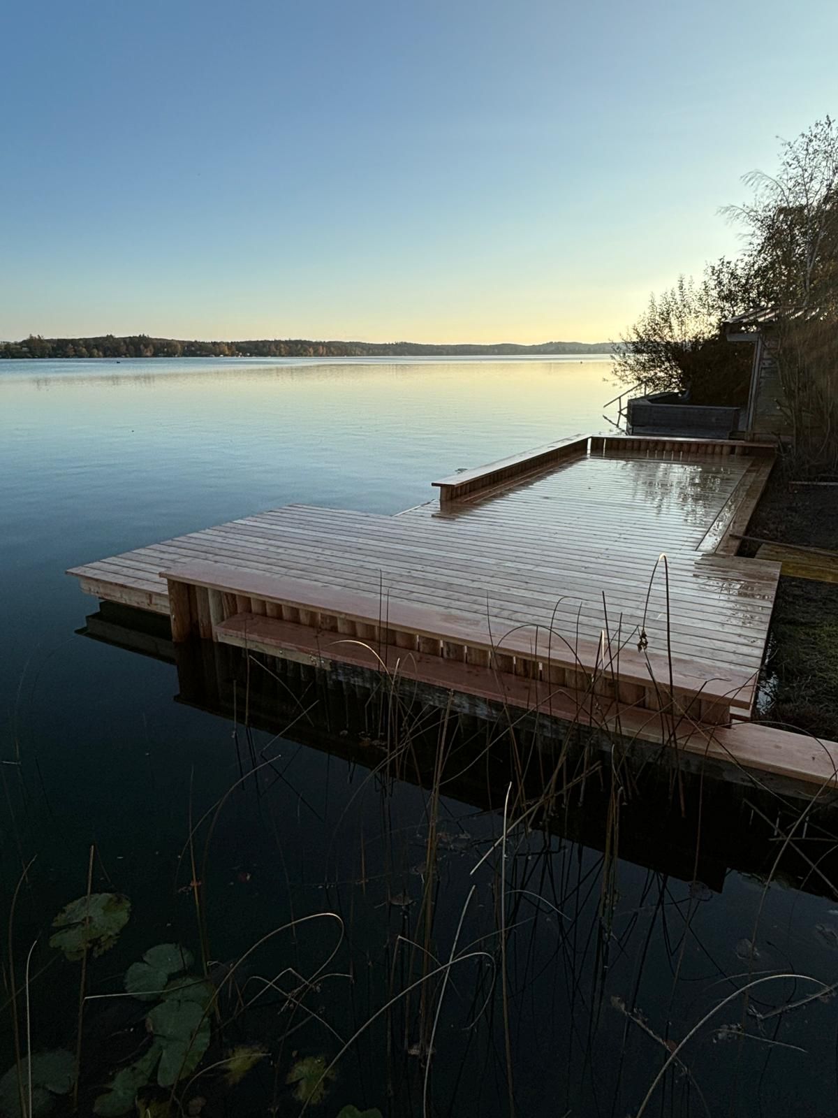 Sonnenuntergang über ruhigem Wasser mit Holzsteg