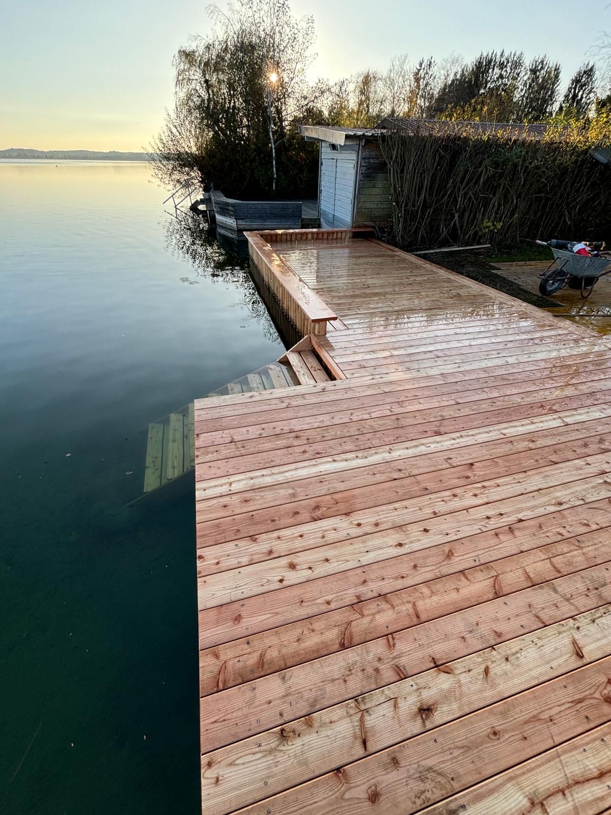 Holzsteg über Wasser mit Schilf und Sonnenuntergang