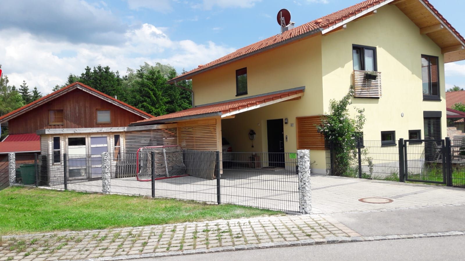 Gelbes Wohnhaus mit rotem Dach und Holzgeländer